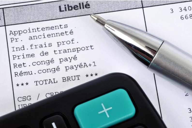 Bulletin de paie, stylo et calculatrice