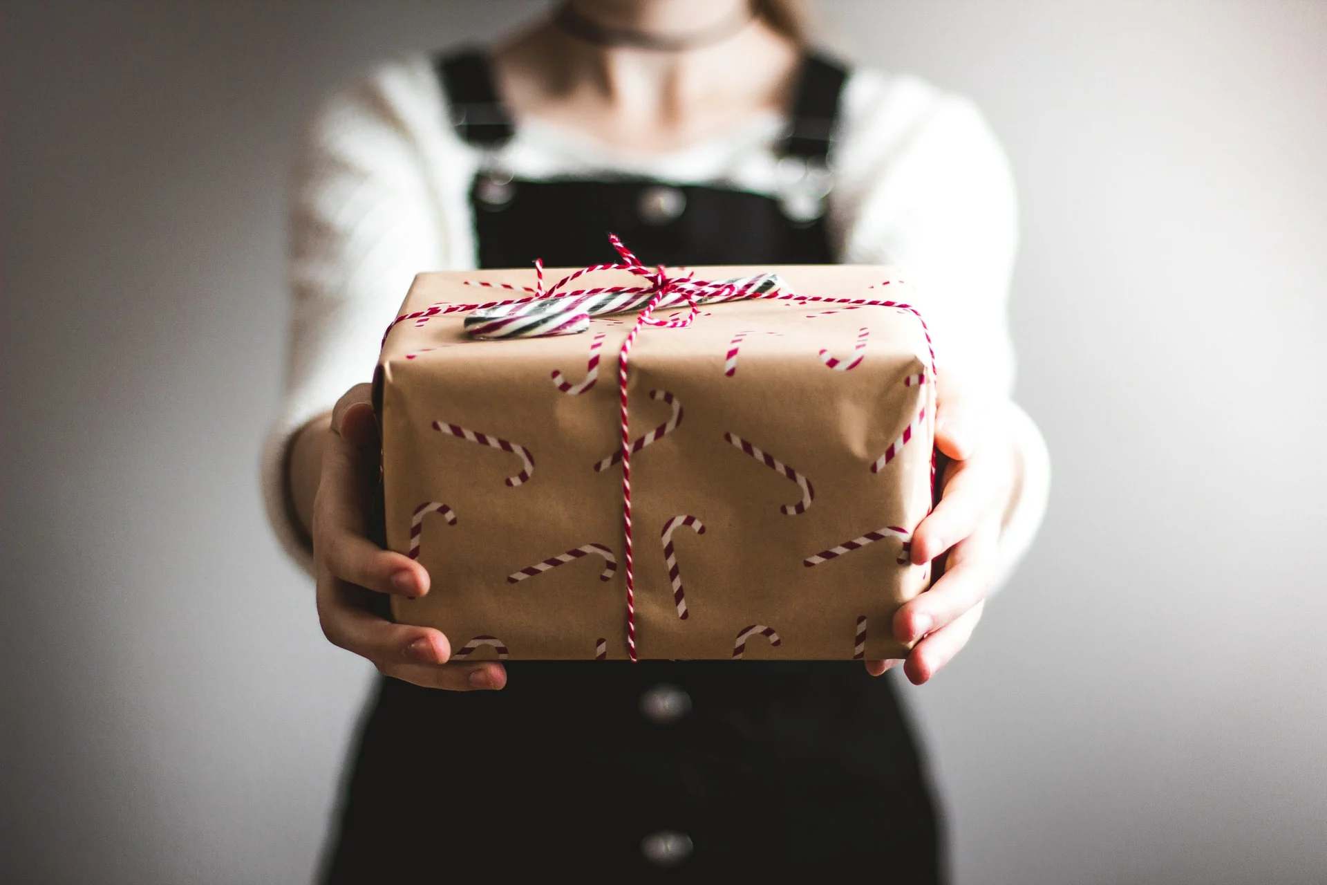 Mains tendant un cadeau emballé dans du papier kraft