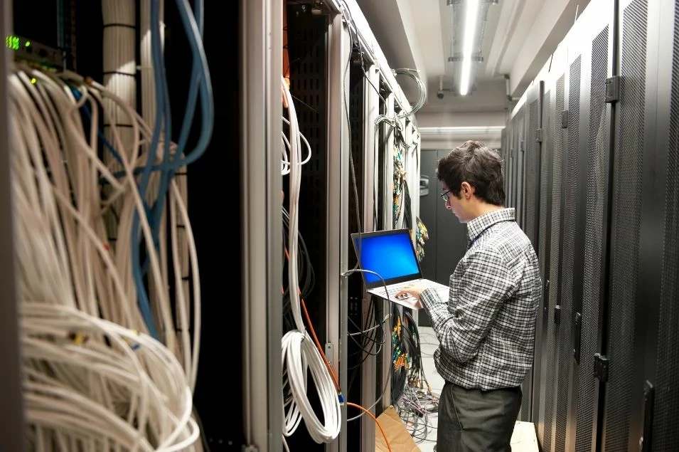 Technicien de maintenance informatique intervenant dans une baie de serveurs